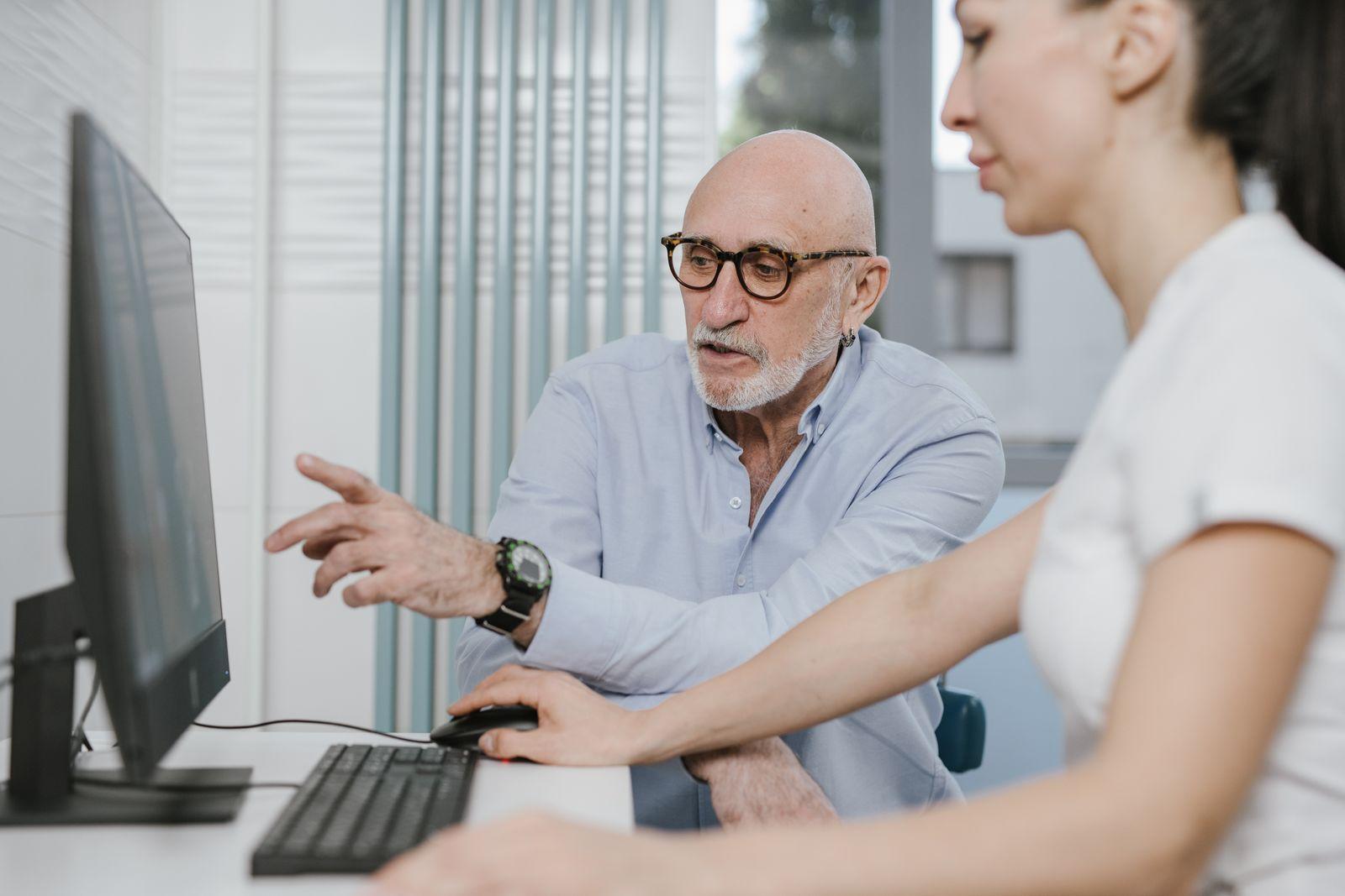 Specialist assisting a colleague at an accessible computer workstation