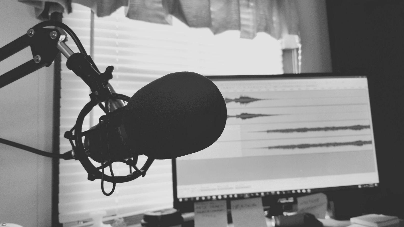 Studio microphone with an audio waveform on a display behind it